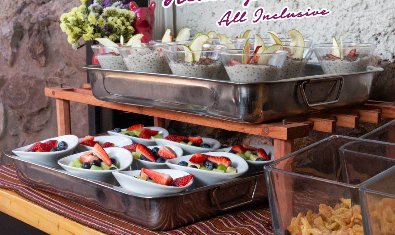 Un bufé con diversos platos, incluyendo cuencos de fruta y una barra de ensaladas.
