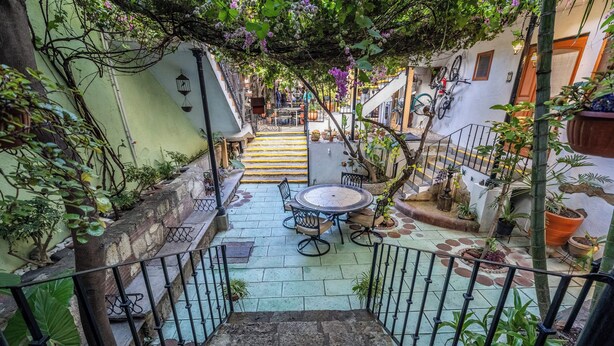 Un patio con una escalera de piedra que conduce a un área de comedor con una mesa redonda y sillas.