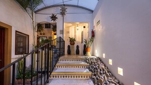 Una escalera estrecha de losas de piedra con barandilla de metal que conduce a una puerta.