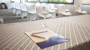 Un salón de conferencias con una mesa dispuesta para una reunión, un vaso de agua y un folleto de Horizon Business & Community.