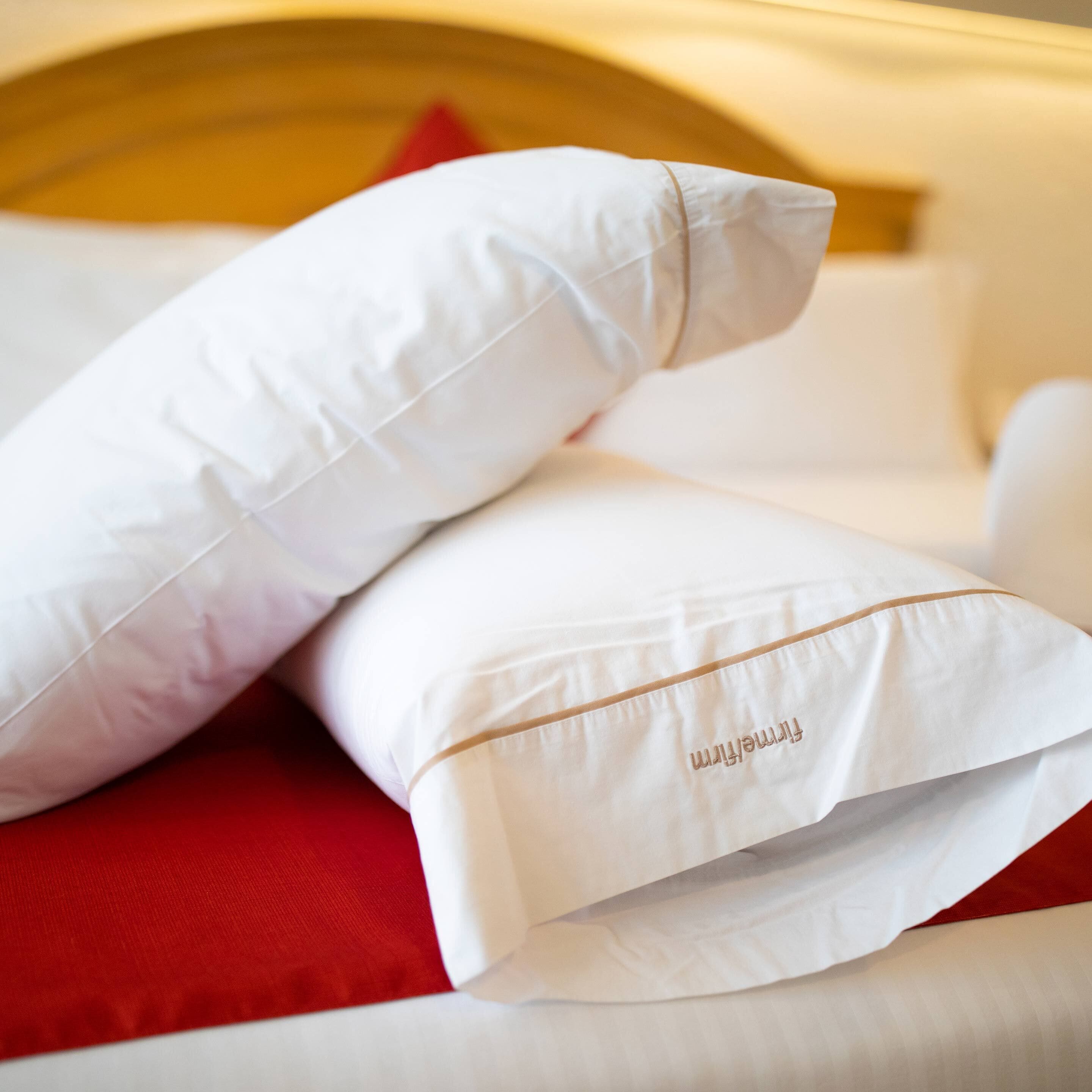A bed with white pillows and a red pillow.