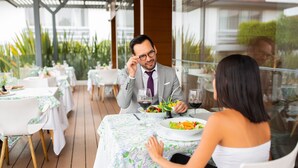 A dining area with tables set for two, featuring floral tablecloths and white chairs. - Hotel Horizon and Convention Center (Morelia)