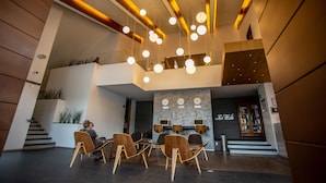 A modern lobby with a seating area, a staircase, and a reception desk. - Hotel Horizon and Convention Center (Morelia)
