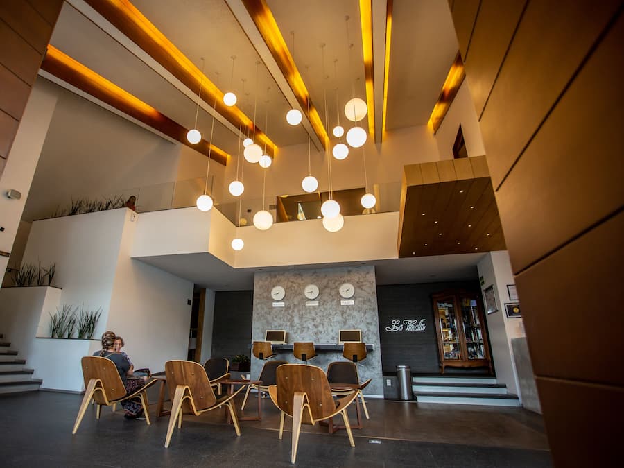 A modern lobby with a seating area, a staircase, and a reception desk.
