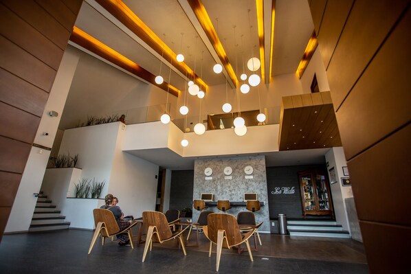 A modern lobby with a seating area, a staircase, and a reception desk. - Hotel Horizon and Convention Center (Morelia)