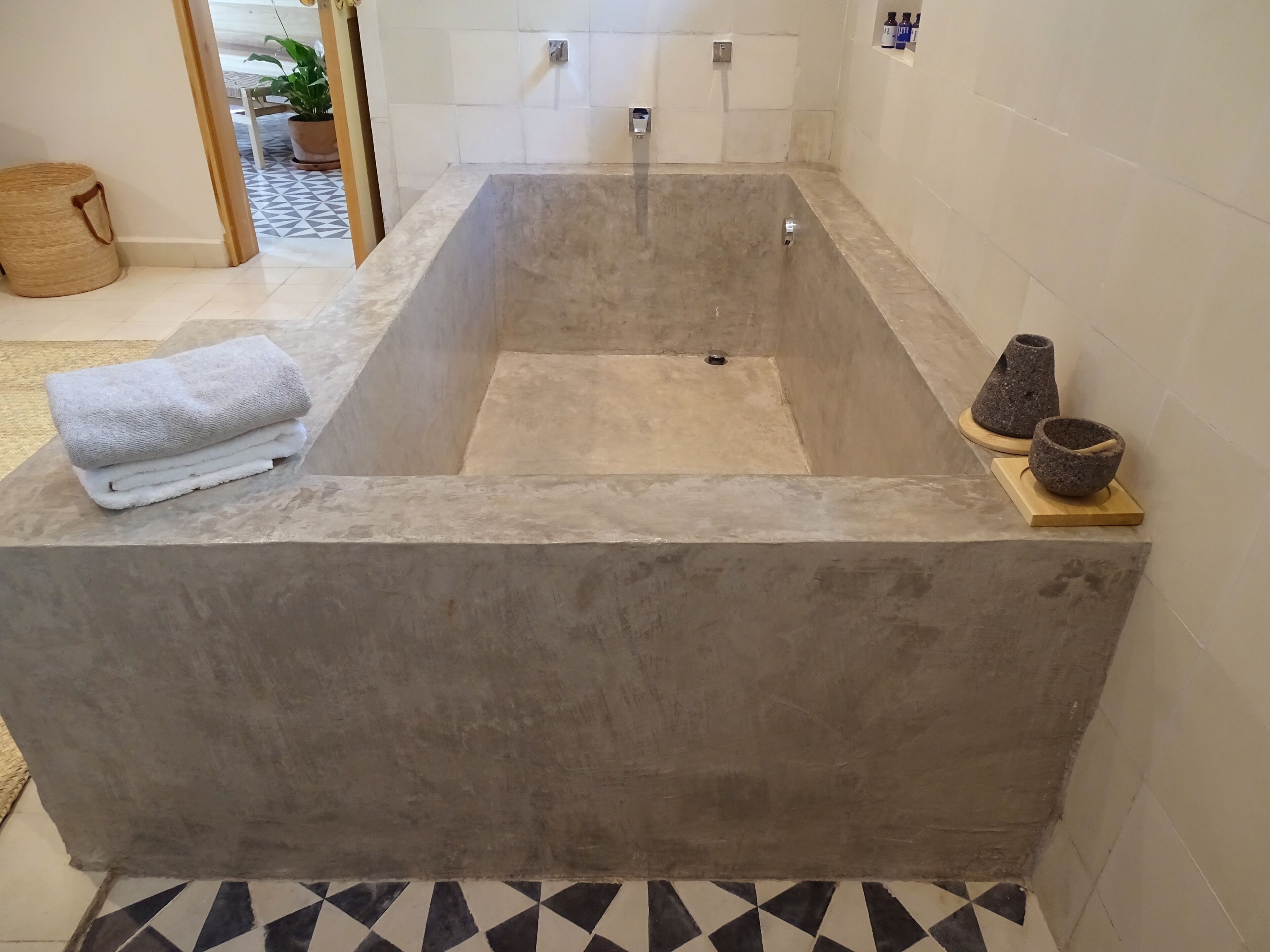 Un baño moderno con una bañera grande, una pila de toallas y dos recipientes de piedra a un lado.