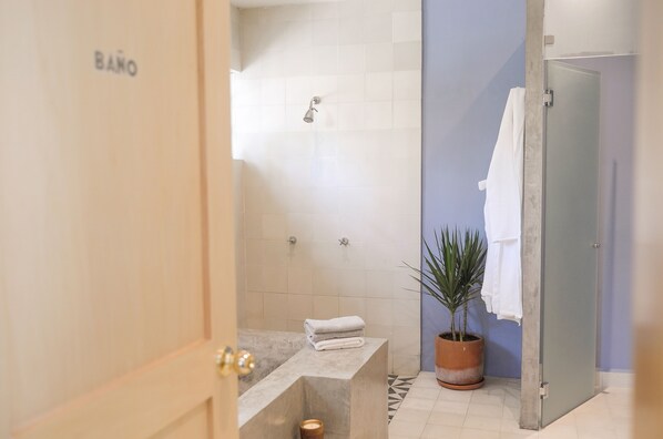 A bathroom with a bathtub, a shower, a potted plant, and a towel rack.