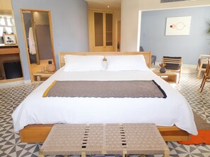 A neatly made bed with a wooden headboard, a bedside table with a lamp, and a chair.