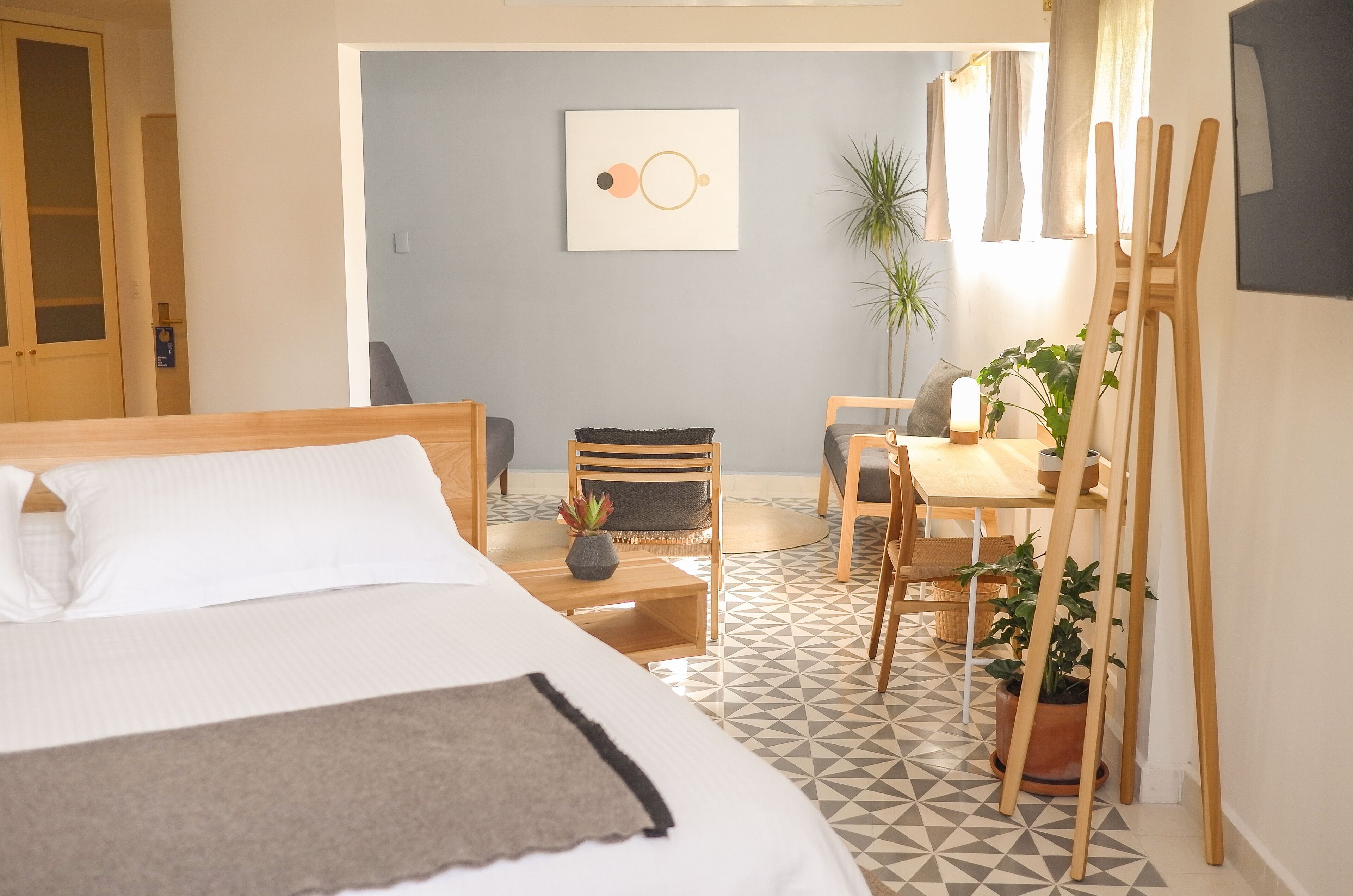 Ein Hotelzimmer mit einem Bett, einem Schreibtisch, einem Stuhl und einer Zimmerpflanze.