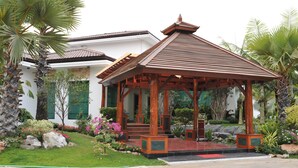 A traditional wooden gazebo with a tiled roof, surrounded by lush greenery and a well-maintained garden. - Palm Spring Resort & Spa (Yangon)