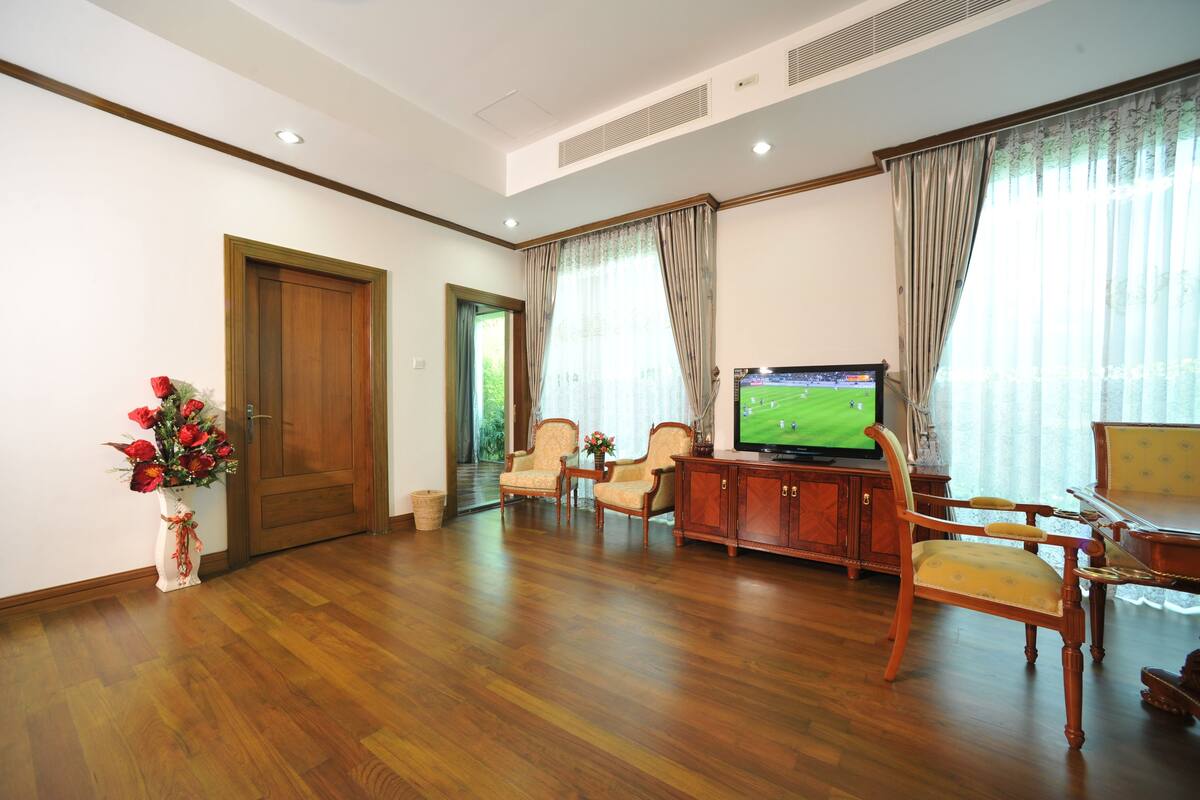 A spacious living room with hardwood flooring, a television, and a wooden cabinet.
