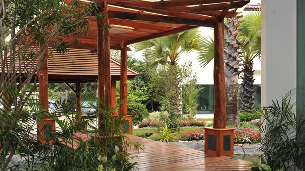 A wooden pergola with a tiled floor, surrounded by lush greenery and a variety of plants. - Palm Spring Resort & Spa (Yangon)