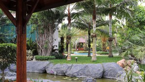 A garden with a pond, rocks, and palm trees. - Palm Spring Resort & Spa (Yangon)