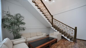 A modern living room with a staircase, a sofa set, a coffee table, and a large plant. - Palm Spring Resort & Spa (Yangon)