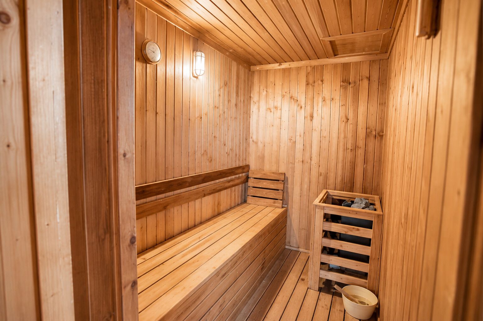 A wooden sauna with benches, a wall-mounted clock, and a small wooden box.