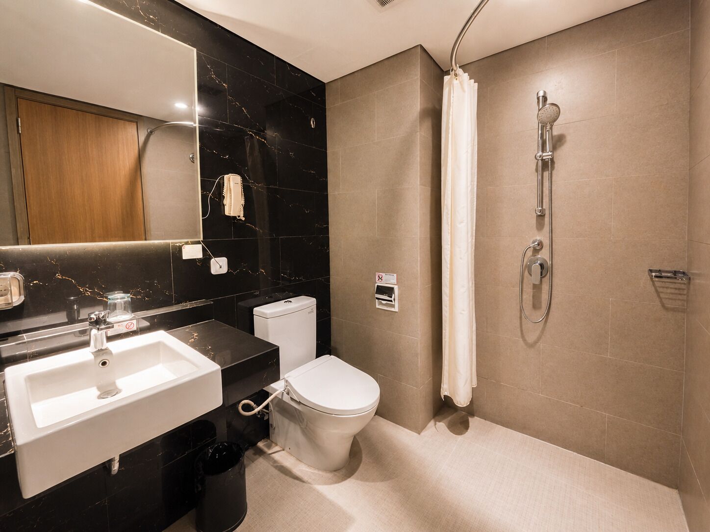 Un baño moderno con lavamanos, inodoro y ducha.