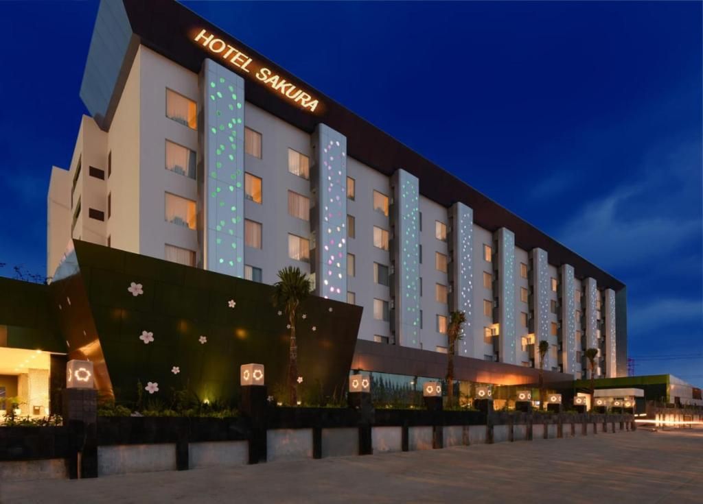 Un hotel de varios pisos con un diseño moderno, que cuenta con una entrada destacada y un letrero que dice 'HOTEL SAKURA'.