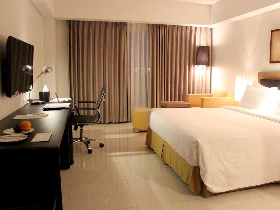 A hotel room with a bed, a desk, a chair, a television, and a window with curtains.