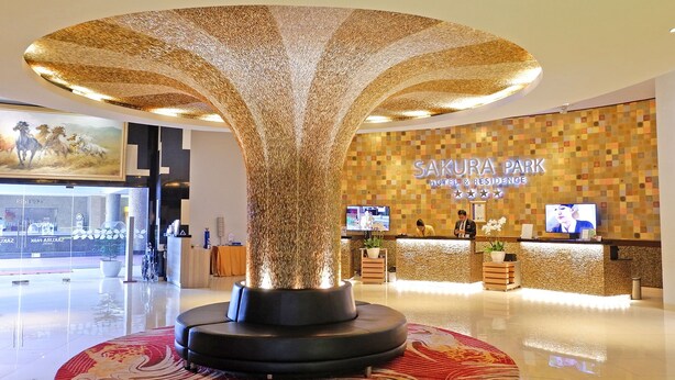 Un hall d’hôtel avec une grande sculpture d’arbre illuminée, un comptoir d’accueil et un mur portant le nom de l’hôtel.
