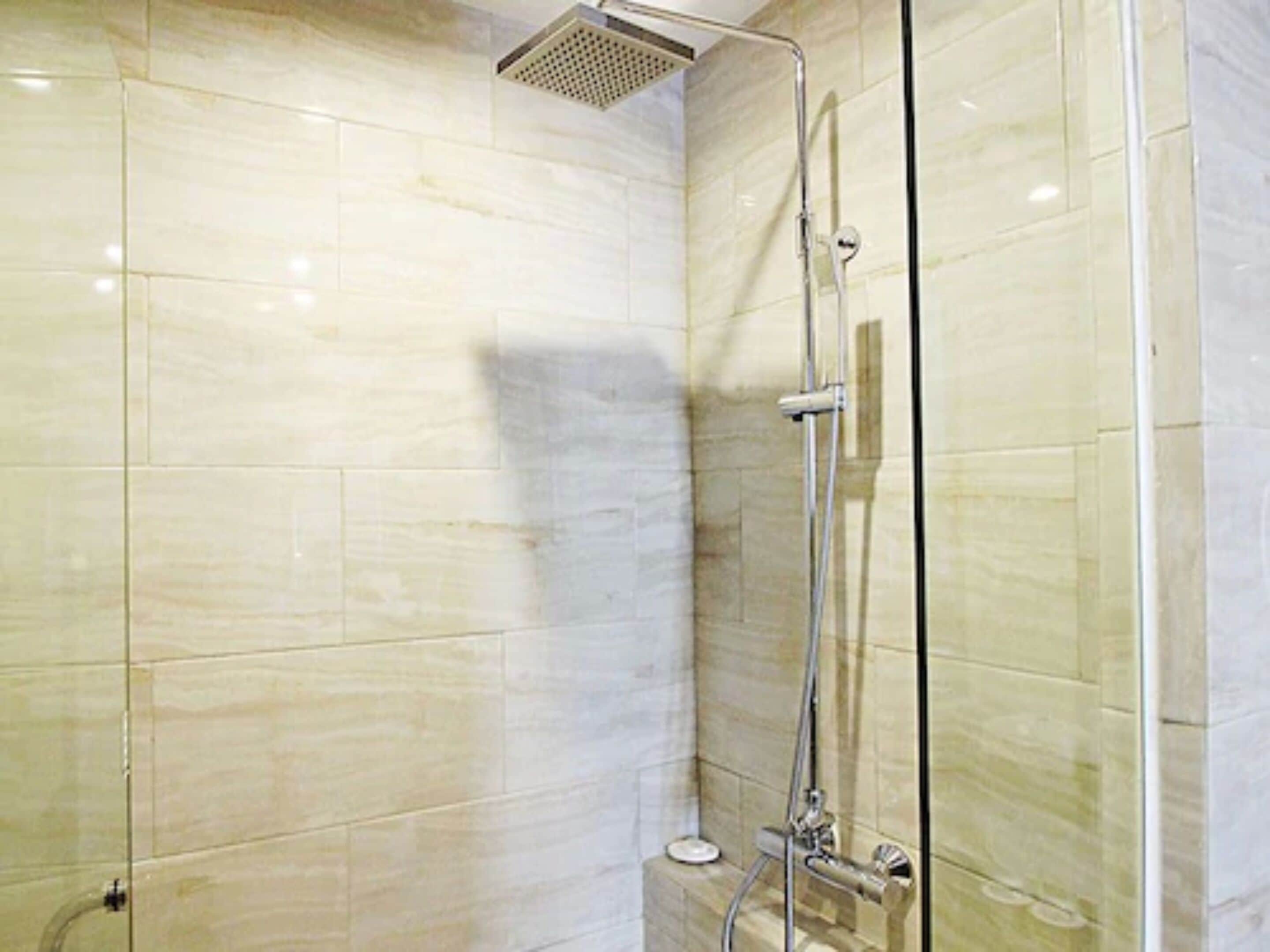 Une douche moderne dotée d’une porte en verre et d’un pommeau de douche à main.