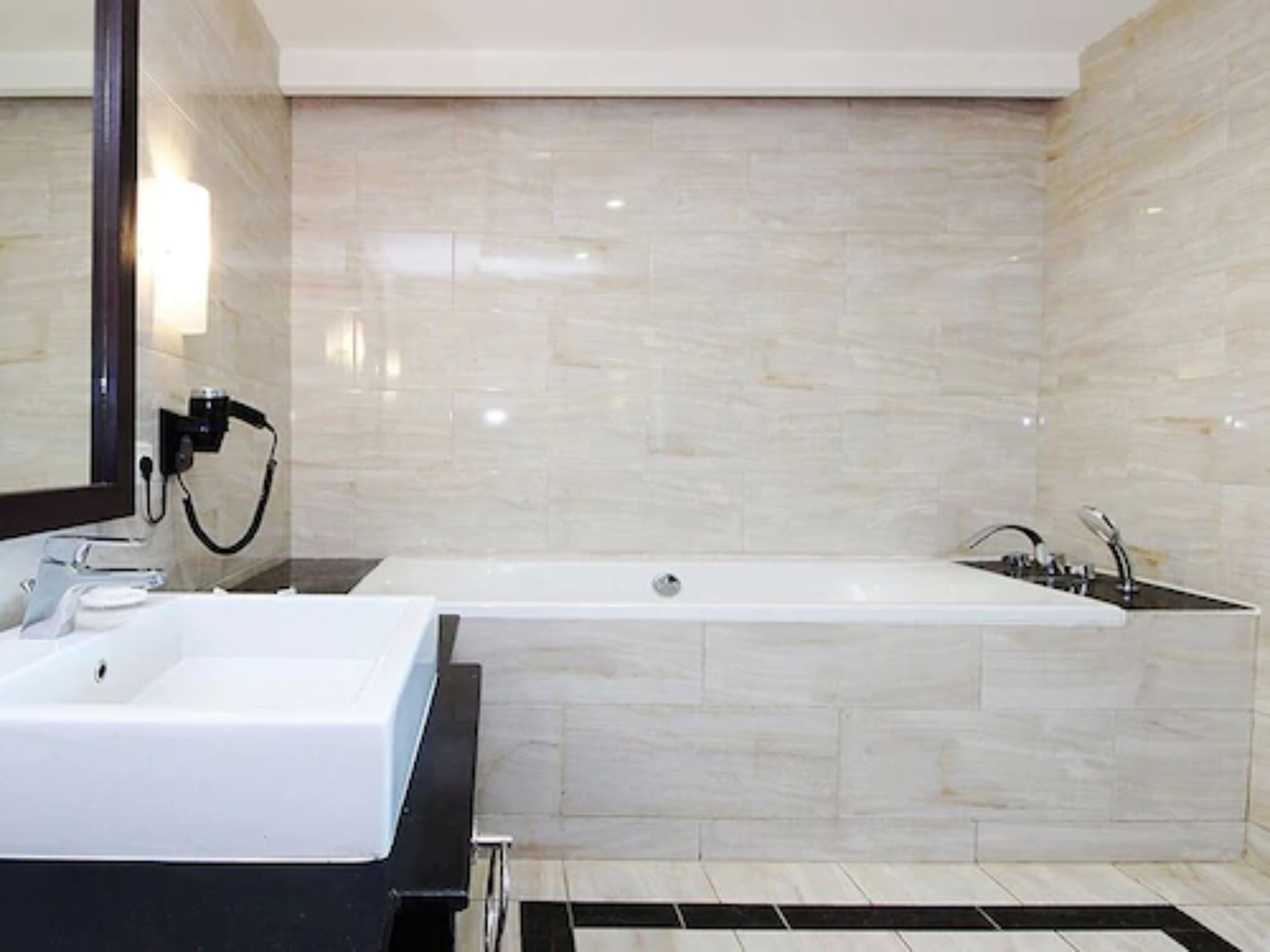 Un baño moderno con una bañera grande, un lavabo independiente y un espejo.
