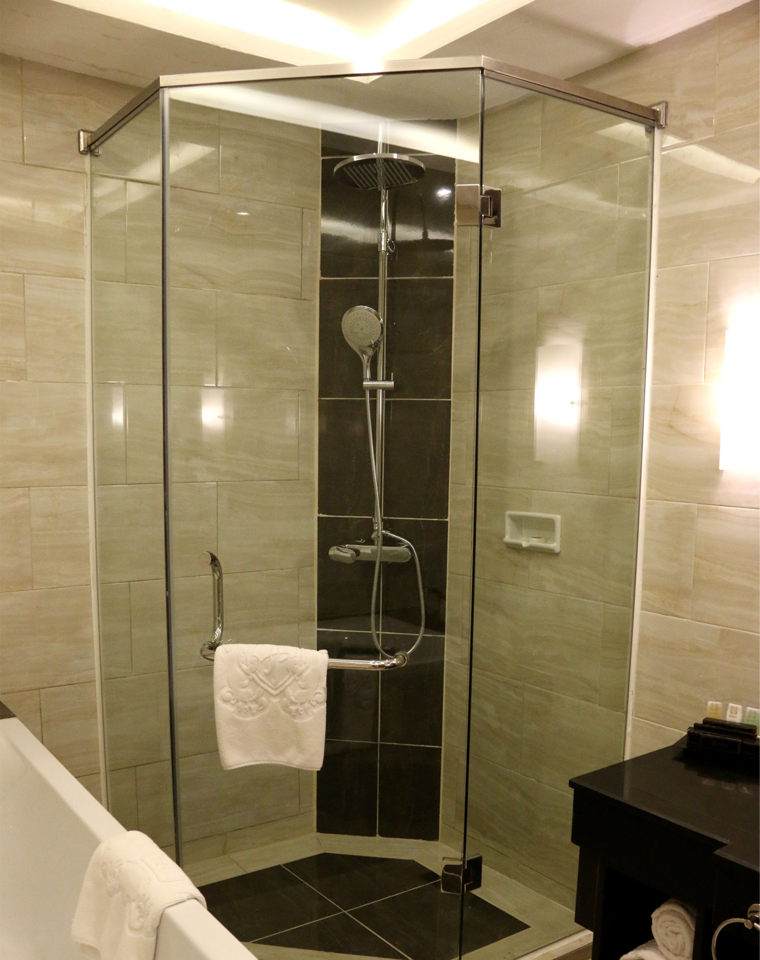 A modern bathroom with a glass-enclosed shower, a white bathtub, and a black vanity.