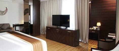 A modern hotel room with a large bed, a TV, a desk, and a chair.