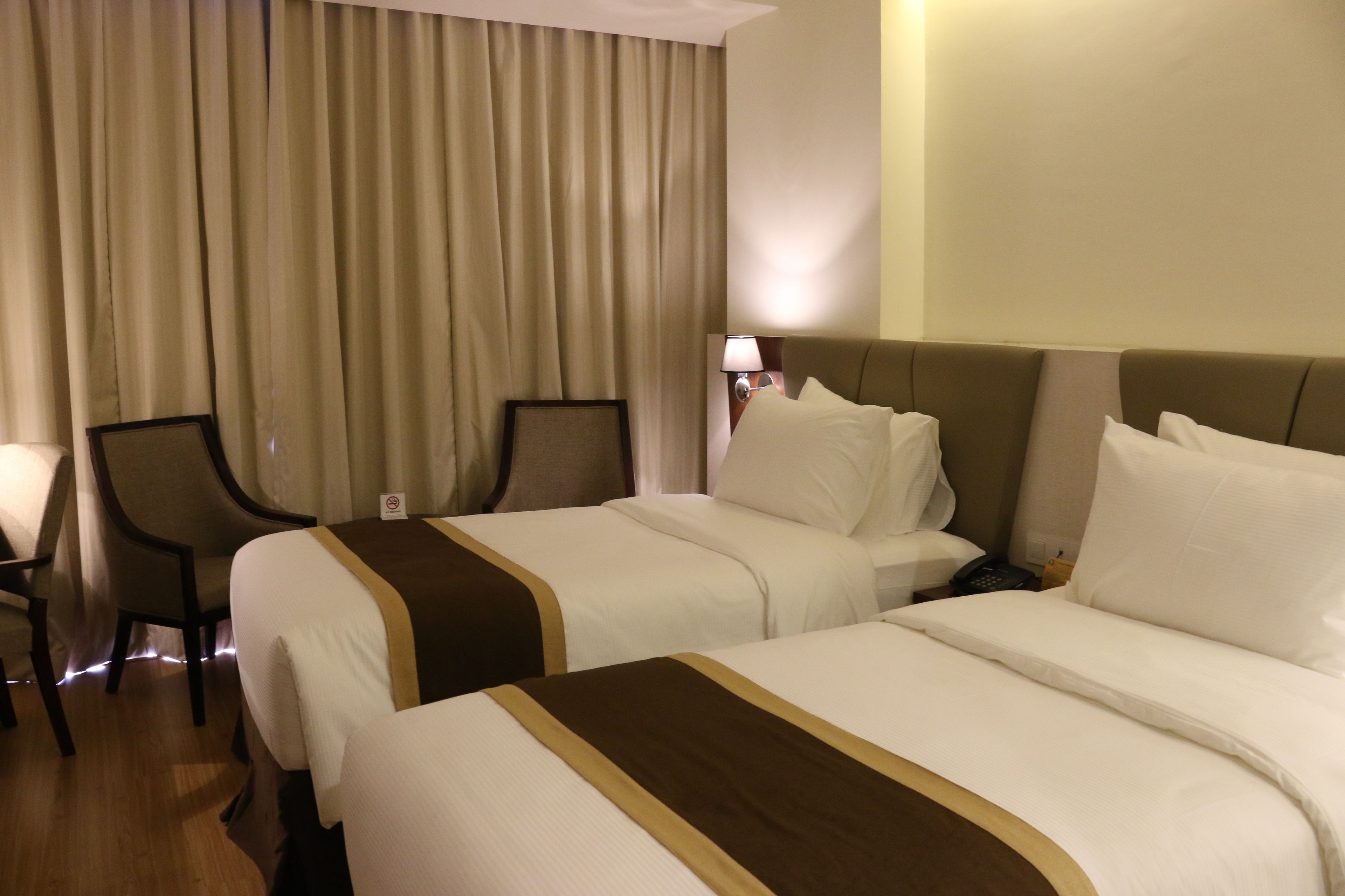 A hotel room with two beds, a desk, and a chair.