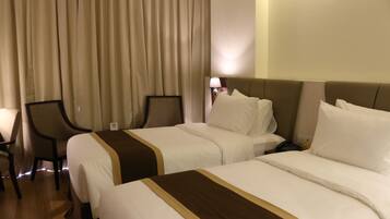 A hotel room with two beds, a desk, and a chair.