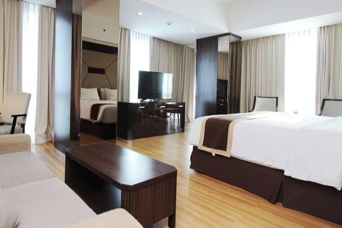 Ein Hotelzimmer mit einem großen Bett, einem Schreibtisch mit Stuhl, einem Fernseher und einem Sofa.