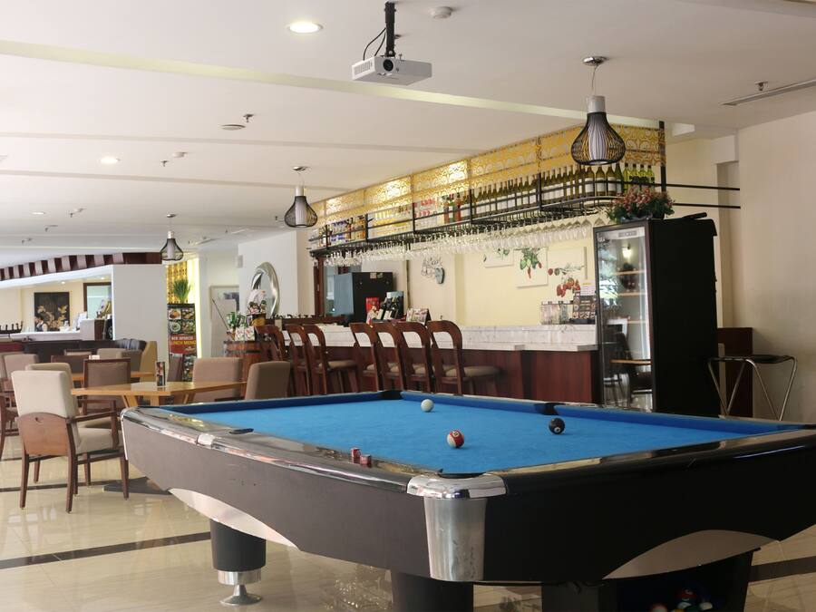 A pool table in a room with a bar area, chairs, and a counter.