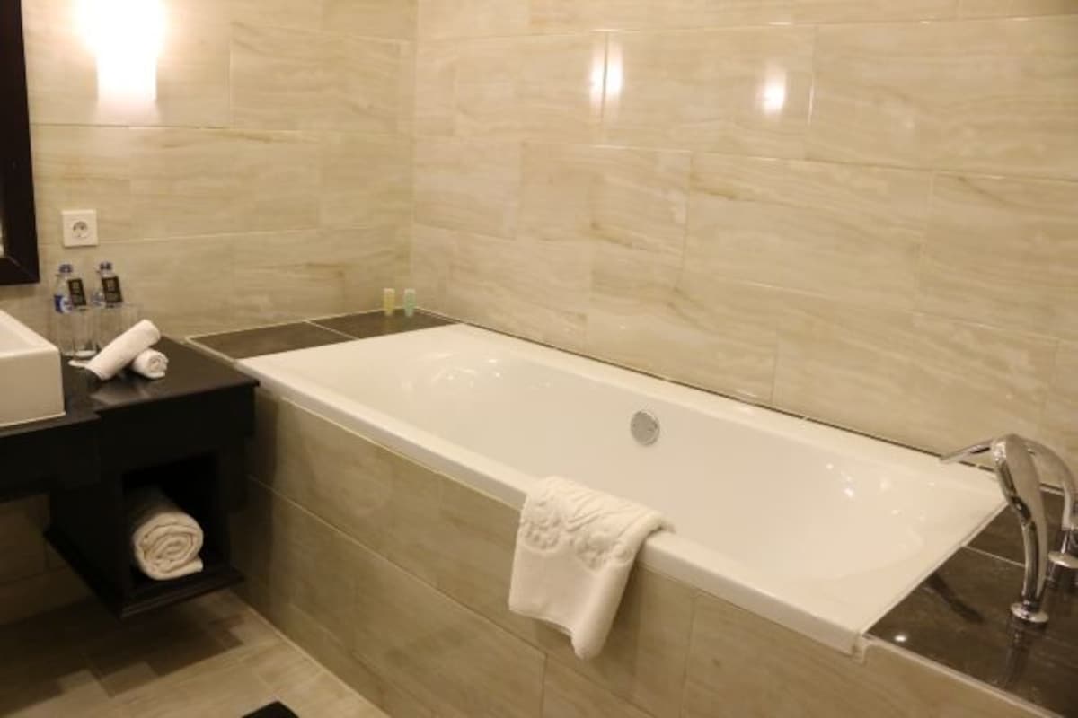 Ein modernes Badezimmer mit einer großen Badewanne, einem dunklen Holzwaschtisch und einem Handtuchhalter.