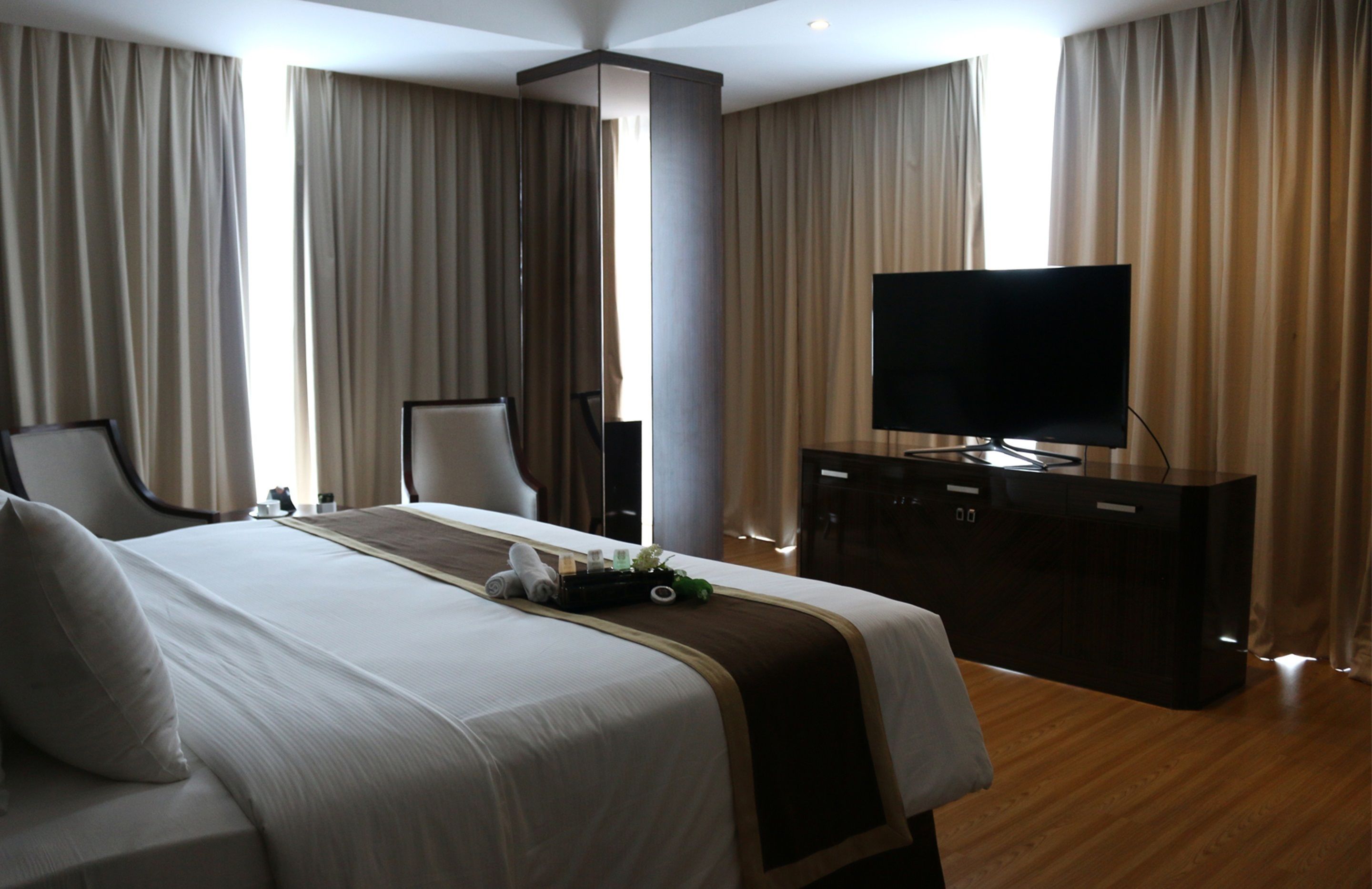 Habitación de hotel con una cama grande, televisión de pantalla plana, escritorio y espejo.