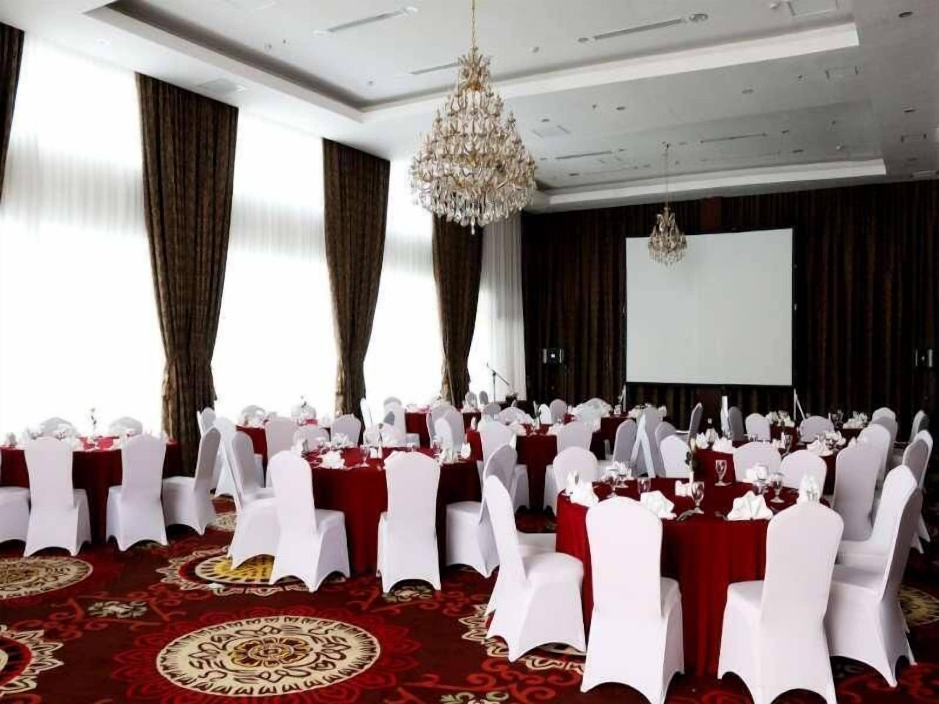 A conference room with round tables, white chairs, and red tablecloths.