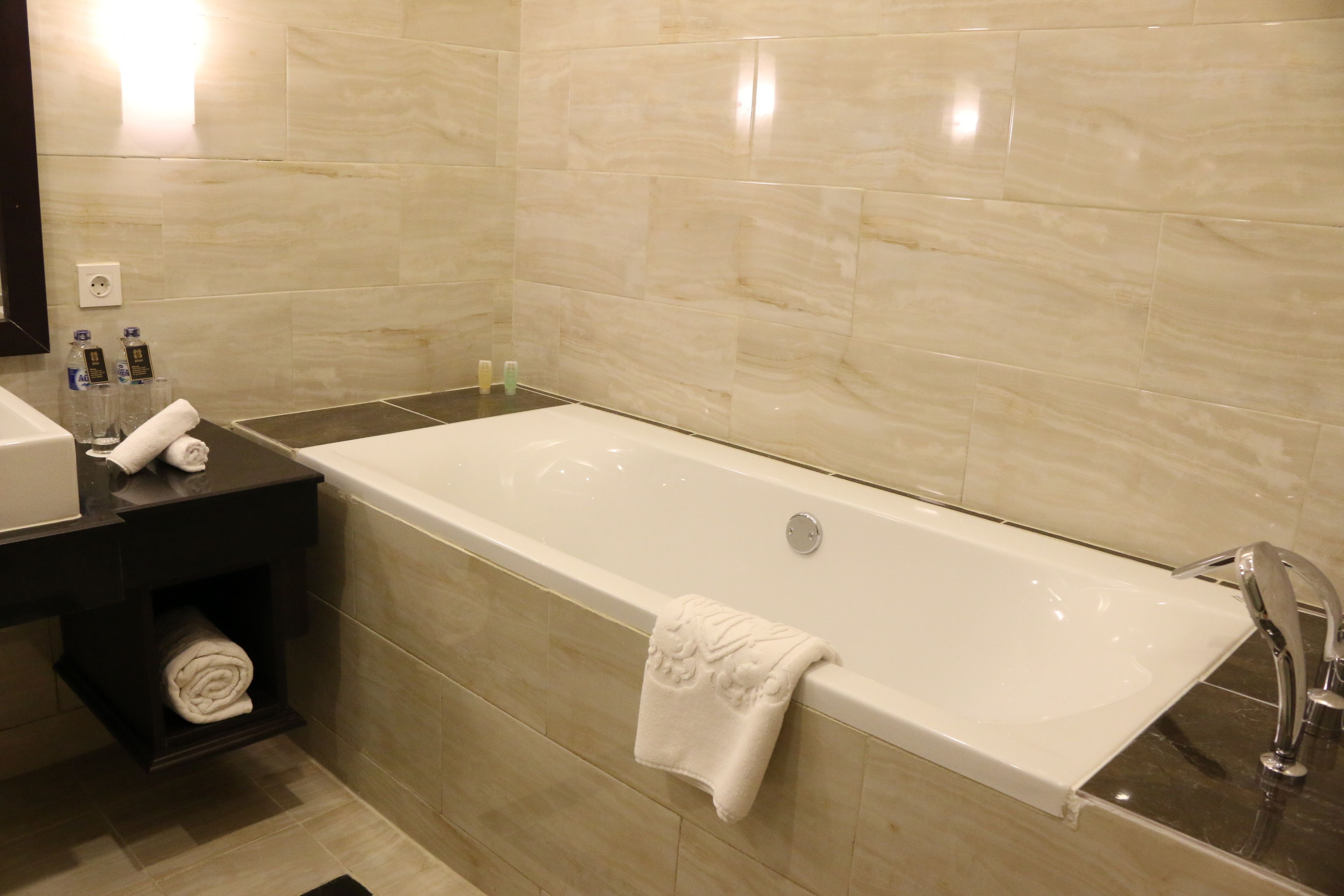 A modern bathroom with a large bathtub, a dark wooden vanity, and a mirror.