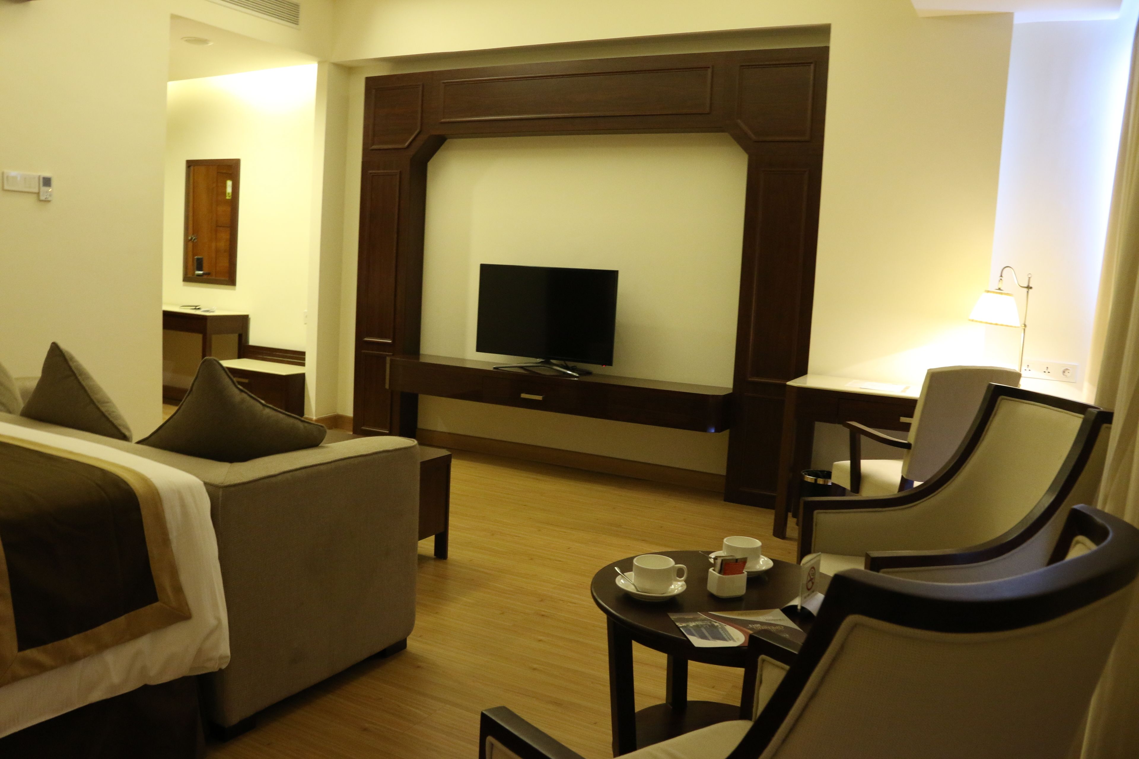 A hotel room with a bed, a sofa, a TV, a desk, and a chair.