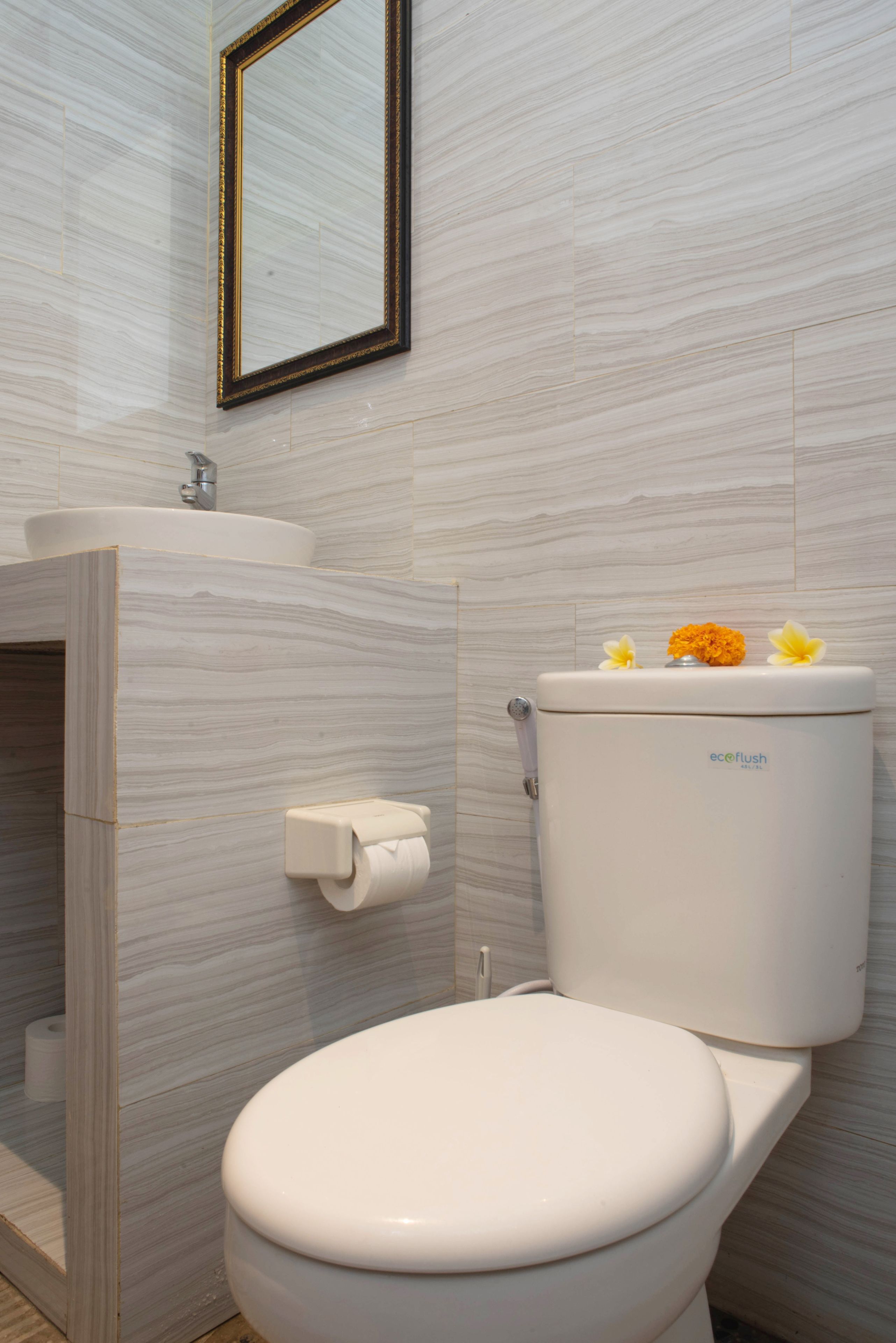 A bathroom with a toilet, sink, and a mirror on the wall.