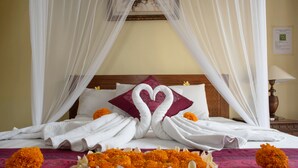 Una cama con toallas blancas, un cojín con forma de corazón y flores de caléndula.