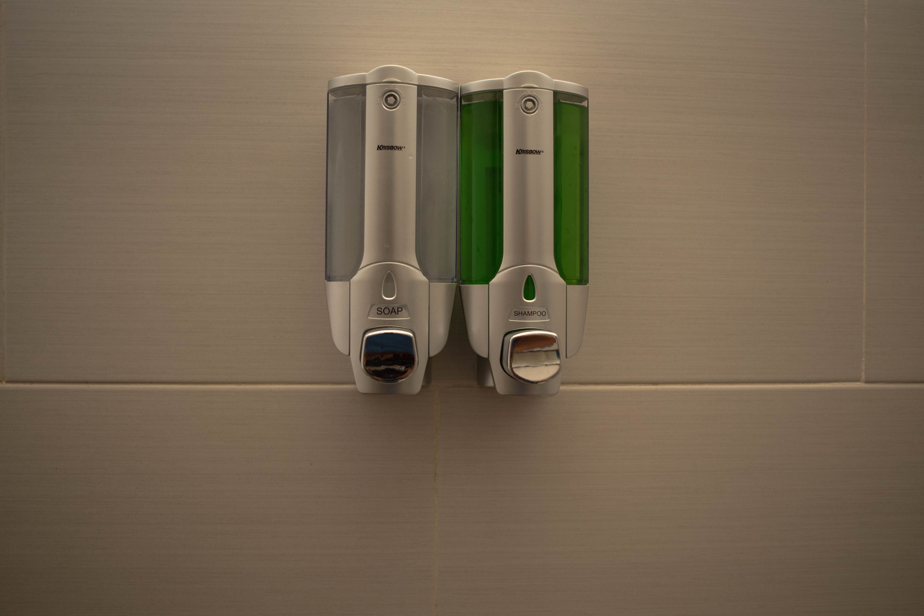 Two soap and shampoo dispensers mounted on a wall.