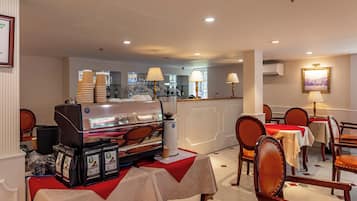 Un comedor de hotel con mesas, sillas, una máquina de café y una barra.