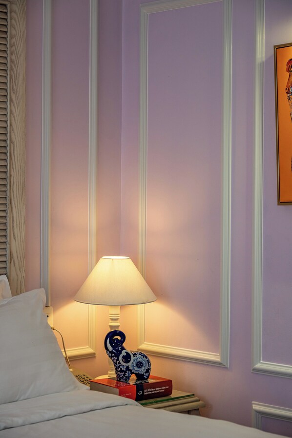 A hotel room with a bed, a bedside lamp, a vase, and books. - Hotel L Odeon Phu My Hung (Ho Chi Minh City)