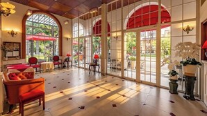 A spacious lobby with large windows, red umbrellas, and a variety of seating arrangements. - Hotel L Odeon Phu My Hung (Ho Chi Minh City)
