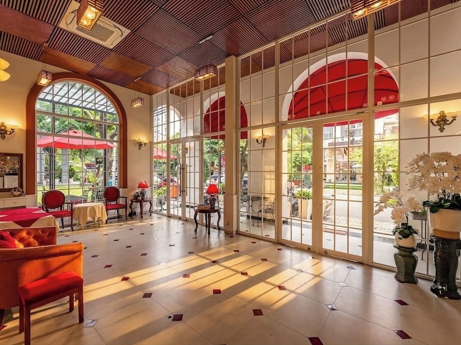 A spacious lobby with large windows, red umbrellas, and a variety of seating arrangements.