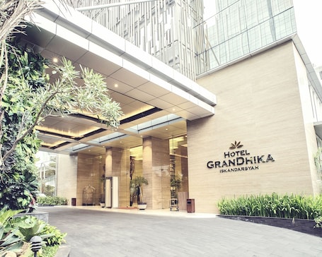 The entrance of Hotel Grandhika with a modern design, featuring a large glass facade and a prominent sign.