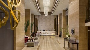 Un hall d’hôtel comprenant un comptoir d’accueil, un espace salon et un lustre.