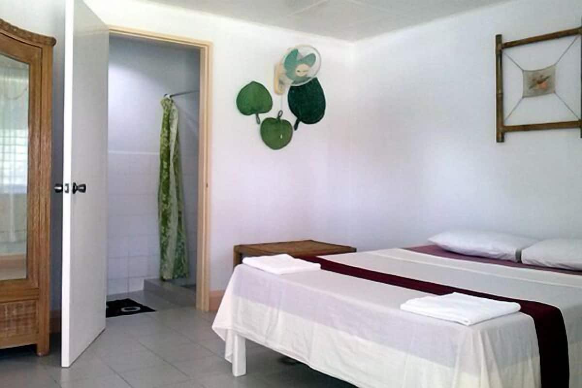 Un dormitorio con cama, mesita de noche, cortina de ducha y un adorno en la pared.