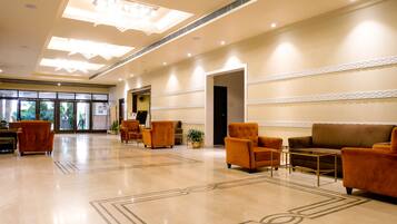 A spacious lobby with a polished marble floor, a reception desk, and seating areas.