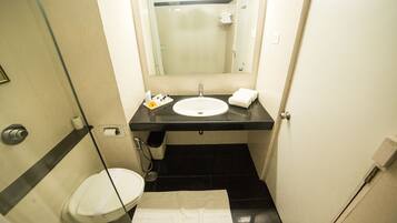 Une petite salle de bain avec un lavabo blanc, un miroir, des toilettes et un porte-serviettes.