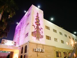 A building with a tower featuring a statue, surrounded by decorative lights.