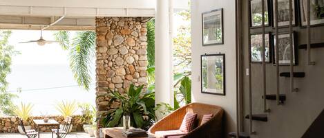 A room with a stone wall, wicker furniture, and framed pictures on the wall.